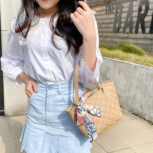 Quilted light brown tote bag with silk scarf accessory shown in an outdoor street setting