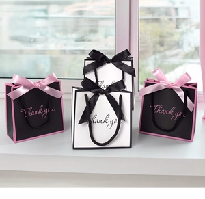 Close-up of small gift bags with silk ribbon bows and Thank You cursive text