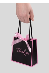 Close-up of black paper gift bag with pink Thank You lettering and satin bow detail