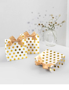 Detail of white paper gift bags with gold foil polka dots and champagne satin bows