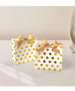 Detail view of mini white gift bags with gold foil dots and champagne satin bows