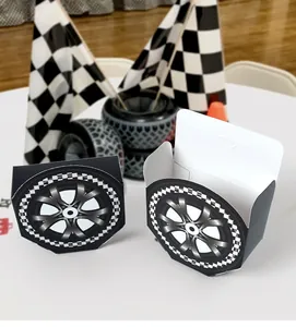 Close-up of tire-shaped racing party favor boxes with checkered flag patterns