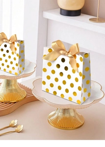 Macro shot of white gift bags with gold foil dots and elegant satin bow handles