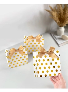 Detailed view of white gift bags with gold polka dots and elegant satin bow knots
