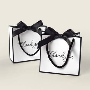 Elegant white paper gift bags with black ribbon bows and Thank You print decoration