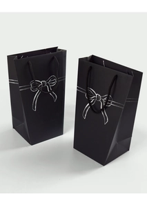 Detail showing matte black gift bag with a white bow design and woven rope handle