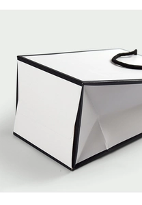 Close-up of the reinforced bottom and folding craft of a minimalist white paper gift bag