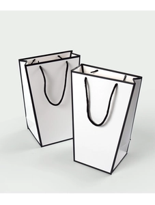 Minimalist white trapezoid paper gift bags with black edges and woven rope handles