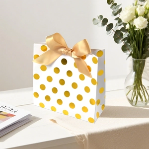 Sacchetto regalo in carta bianca a pois dorati con un grande fiocco di nastro di raso