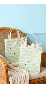Detail of green and white striped gift bags with silk bows on a vintage chair