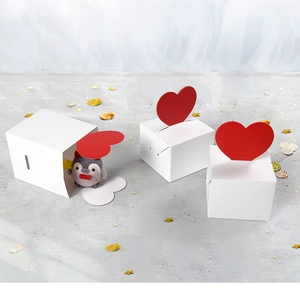 Macro shot of white gift boxes with red heart-shaped tabs and a cute penguin inside