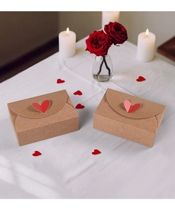 Kraft paper gift boxes with red heart clasp closure on a romantic white fabric background