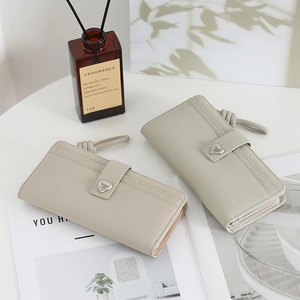 Detail view of beige long wallets with heart metal buckles and wristlet on a table
