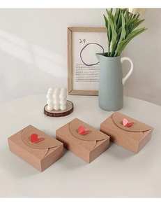 Detail of kraft paper envelope gift boxes with red heart closure and paper texture