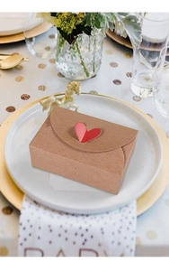 Detail of kraft paper gift box with a red 3D heart-shaped lock on a white ceramic plate
