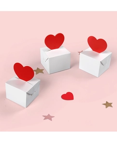Close-up of white gift boxes with red heart-shaped toppers on pink background