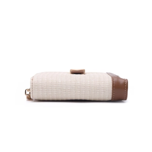Detail of minimalist cream woven wallet with brown leather trim and gold snap closure