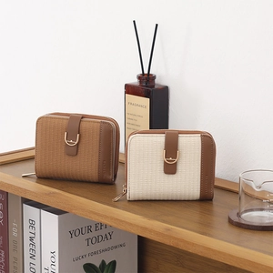 Close-up of woven texture short wallets with metal buckles on a rustic wooden shelf