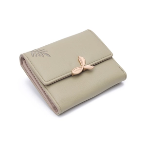 Detail of sage green trifold wallet showing leather texture and leaf-shaped metal clasp