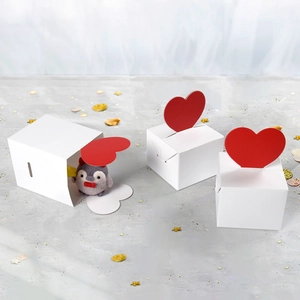 Set weißer Geschenkboxen mit rotem Herzverschluss und Plüschpinguin im Inneren