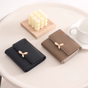 Close-up of short PU leather wallets featuring metal leaf buckle and lychee grain texture