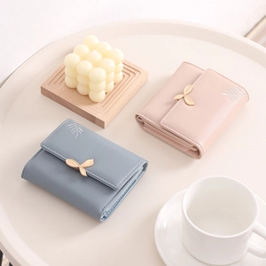 Detail of short tri-fold PU leather wallet with leaf embroidery and metal buckle