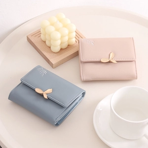 Close-up of elegant leaf-shaped metal clasps on blue and pink leather wallets