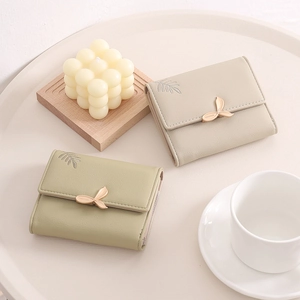 Close-up of PU leather wallets with leaf buckle and embroidery on a round tray