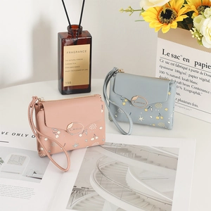 Pink and blue floral PU leather wallets with cherry patterns and hand straps in a soft setting