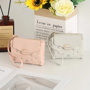 Detail of floral printed PU leather wallets in pink and grey with gold brand logo