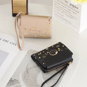 Detail of floral printed women's wallets with gold hardware and removable wrist straps