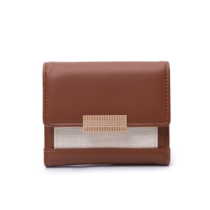 Detail of short tri-fold wallet with brown leather, beige fabric and gold metal bar