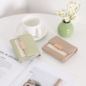 Close-up of minimalist trifold wallets in green and khaki with gold metal buckles