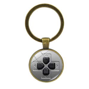 Macro detail of bronze video game controller D-pad keychain with glass dome and metal ring