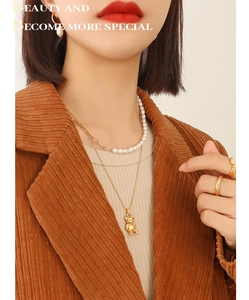 Détail d'un collier pendentif ours doré et bijoux en perles superposés sur un modèle