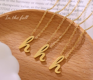 Détail de trois colliers en acier inoxydable plaqué or 18k avec pendentif lettre H cursive