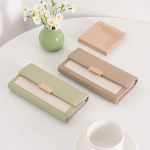 Detailed view of color-block long wallets in soft green and khaki with metal buckles