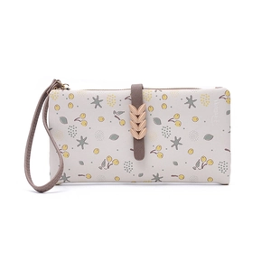 Detailed view of floral long wallet featuring a metal leaf clasp and wristlet strap