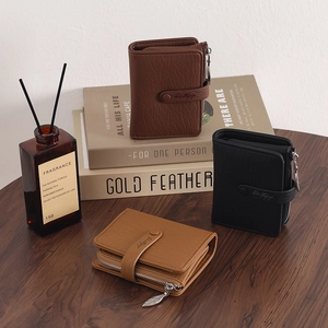 Detailed view of leather wallets with leaf zipper puller on a rustic wooden desk