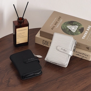Detail of mini leather card holders in black and silver with leaf zipper and buckle