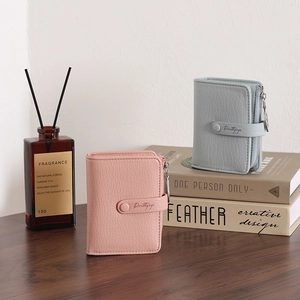 Close-up of pebble leather texture and metallic zippers on pink and blue mini wallets