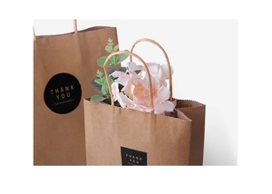 Detail of brown kraft paper gift bag with zigzag edge and gold Thank You sticker