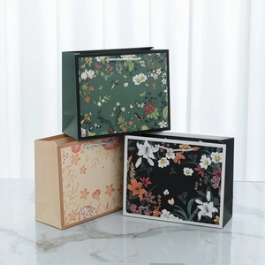 Detailed view of floral paper gift bags with elegant bird patterns and silver woven handles