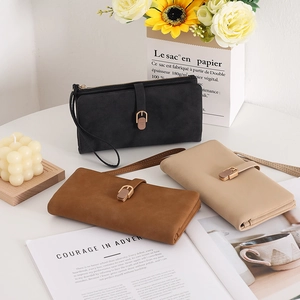 Three long frosted wallets in black, brown, and beige with wristlet straps and metal buckles
