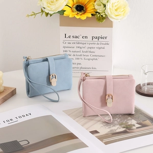 Detail of light blue and pink faux suede mini wallets with zipper closure and wrist strap