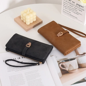 Flat lay of black and brown frosted leather long wallets with wristlets on a desk