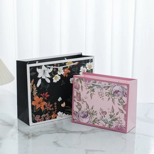 Close-up of floral print gift bags in black and pink with durable woven handles