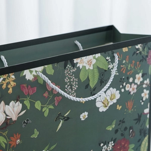 Close-up of floral gift bag with hummingbird print and white woven rope handles