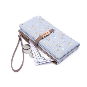 Long light blue floral wallet with gold leaf charm and wristlet strap shown at 45-degree angle