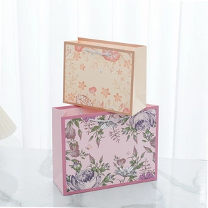 Macro view of floral paper gift bags with woven handles on a white marble surface